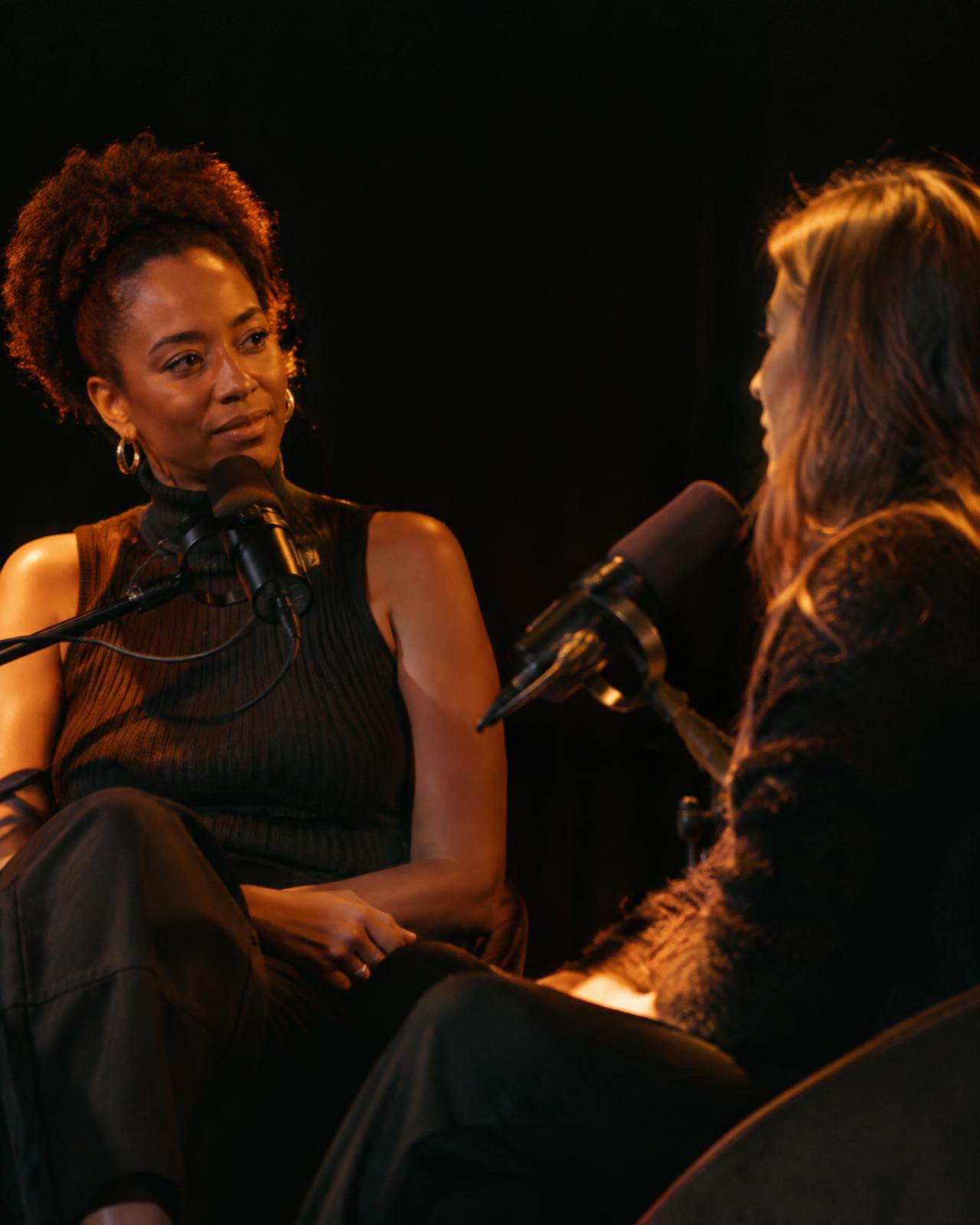 Two women recording a live podcast conversation on stage